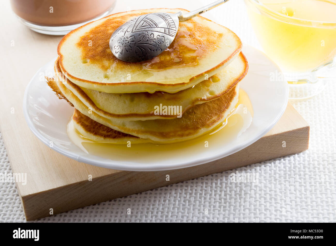Pfannkuchen mit Honig und vintage Silver Spoon auf einer weißen Platte für ein süßes Frühstück mit einer geringen Tiefenschärfe Stockfoto