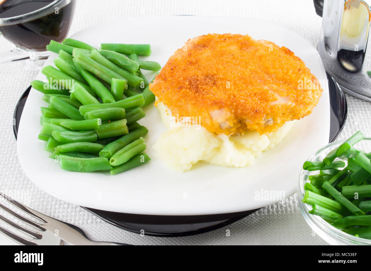 Stück Huhn gebraten paniert, grüne Bohnen und Kartoffelpüree als Beilage auf einem weißen Teller closeup Stockfoto