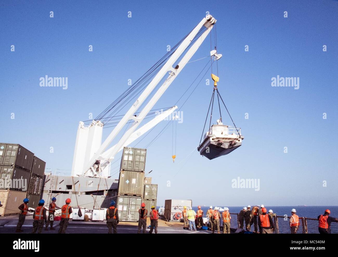 FUJAIRAH, Vereinigte Arabische Emirate (Jan. 17, 2018) U.S Navy Sailors, zu Naval Cargo Handling Bataillon 1 zugewiesen, die Arbeit mit der Crew der USNS Seay (T-AKR 302) ein Dienstprogramm Boot während Native Fury 18 zu heben. Die Übung ist so konzipiert, Special Purpose Marine-Air - Masse Aufgabe Force-Native Fury Marines und US-Marine Seeleute in maritime Vorpositionierung kraft Operationen zu trainieren und zielt darauf ab, die Kenntnisse zu verbessern, erweitern die Zusammenarbeit im maritimen Fähigkeiten zu verbessern und die langfristige Stabilität in der Region und die Interoperabilität zwischen den Vereinigten Arabischen Emiraten und in den USA (U.S. Marine Foto von Masse Commun Stockfoto