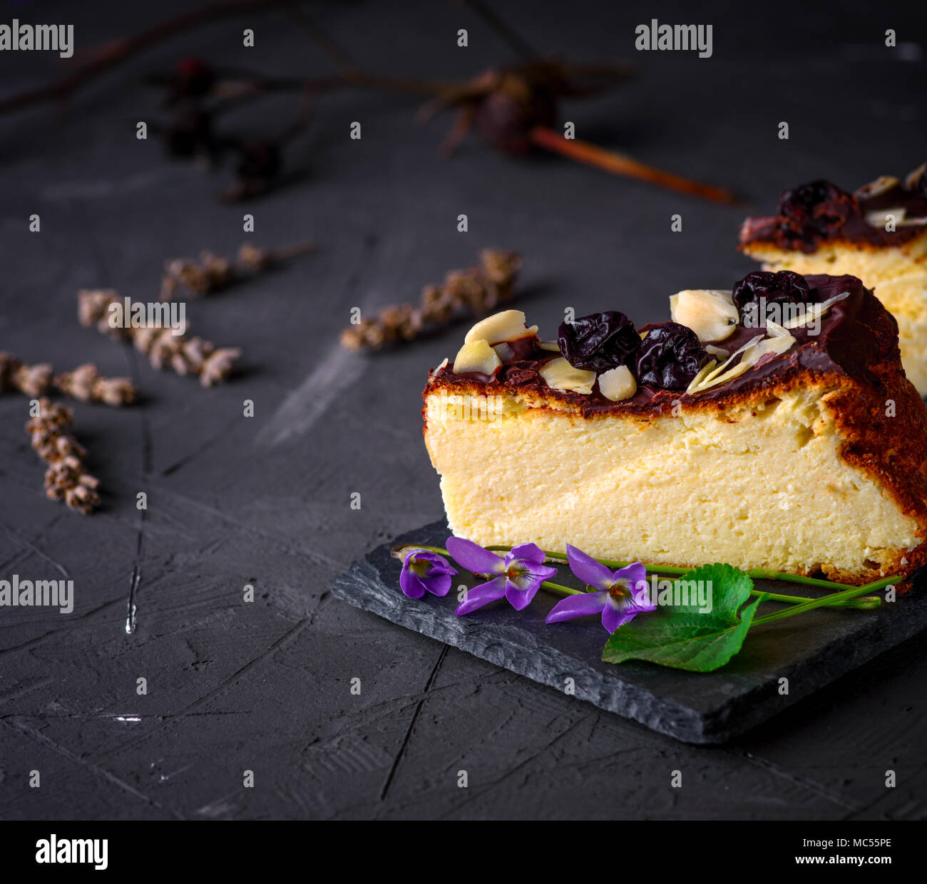 Stück Käsekuchen mit Schokolade und Mandeln Späne auf einem schwarzen Hintergrund gegossen, leeren Raum Stockfoto