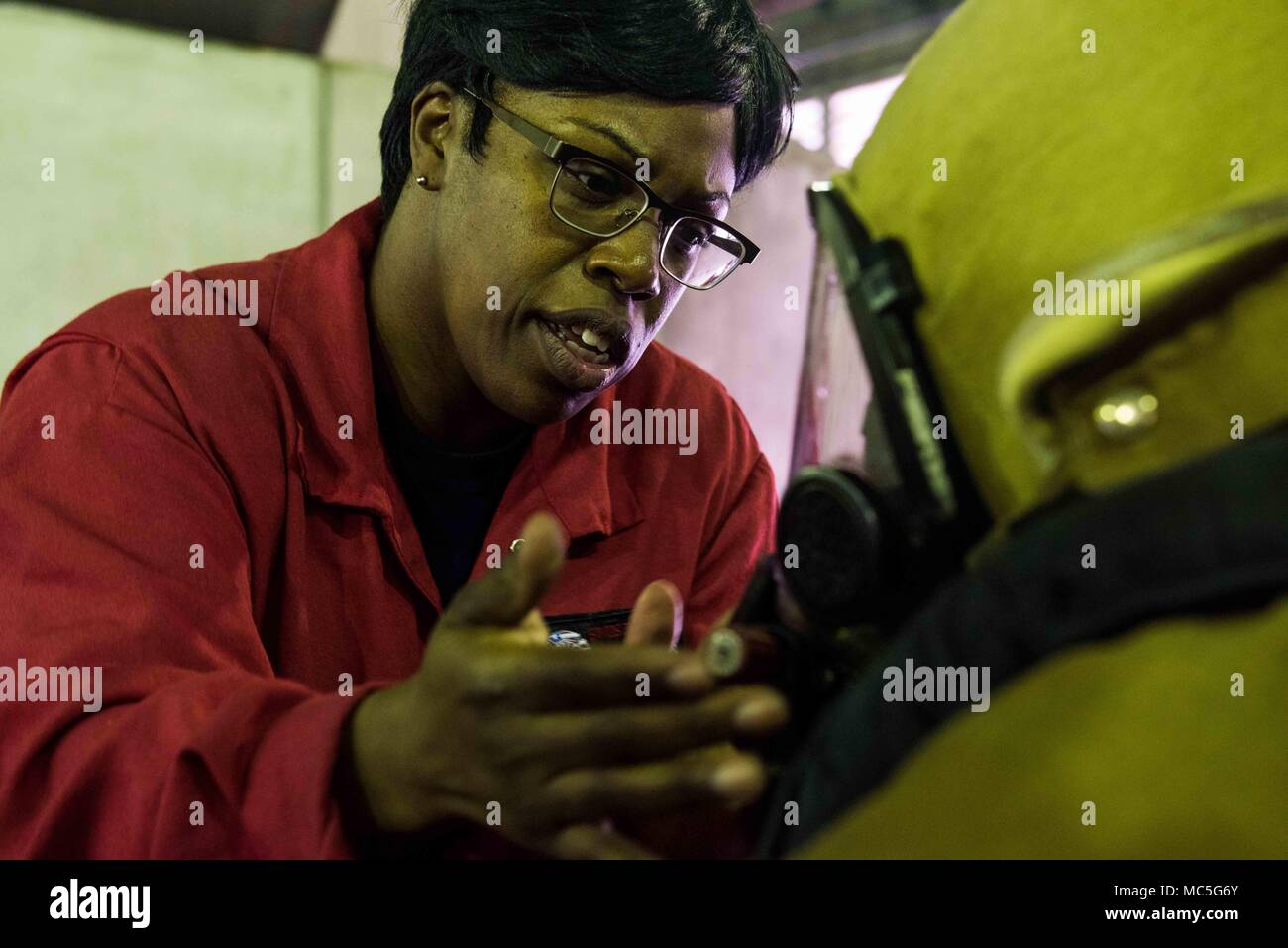 180403-N-ist 471-0215 Yokosuka, Japan (Apr. 3, 2018) Schäden Controlman 1. Klasse Nakia Bugg, von Cobb County, Georgia, unterstützt eine Sailo auf die marine Vorwärts - bereitgestellt Flugzeugträger USS Ronald Reagan (CVN 76) Für eine ordnungsgemäße Dichtung auf eine Brandbekämpfung Maske während der Ausbildung an der Yokosuka Brandbekämpfung und Beschädigungen der Anlage zu prüfen. Ronald Reagan, das Flaggschiff der Carrier Strike Group 5, bietet eine Bekämpfung bereit, Kraft, schützt und verteidigt die kollektive maritime Interessen seiner Verbündeten und Partnern in der Indo-Asia-Pazifik-Region. (U.S. Marine Foto von Massenkommunikation Spezialist Stockfoto