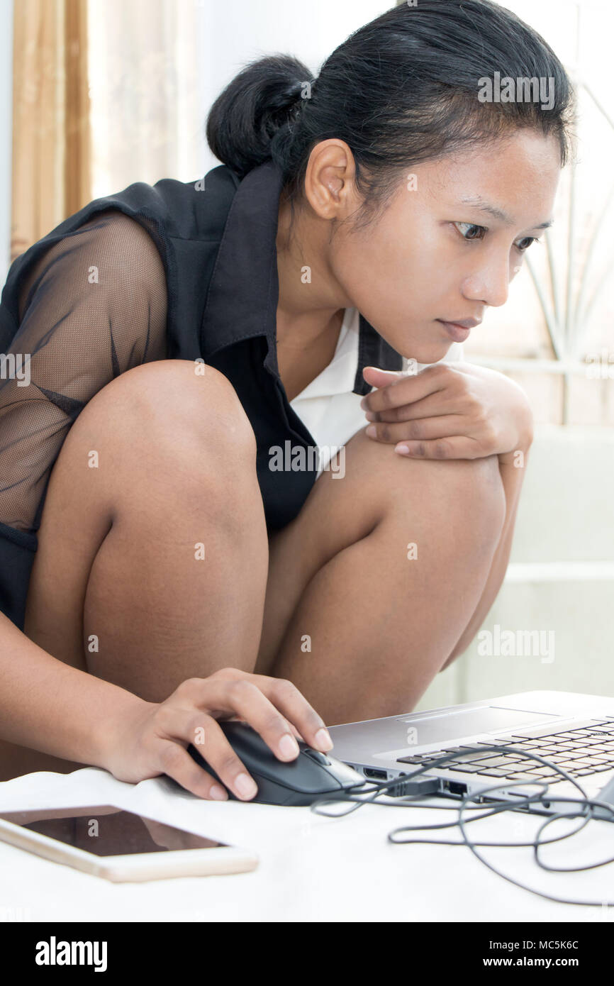 Eine junge Frau, die auf ihrem Laptop auf dem Bett. Eine nachdenkliche Mädchen schreibt auf Computer im Schlafzimmer. Stockfoto