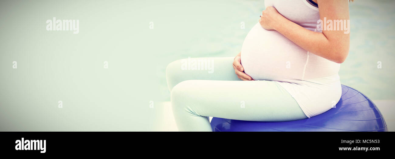 Seitenansicht der schwangeren Frau sitzt auf der übung Kugel Stockfoto