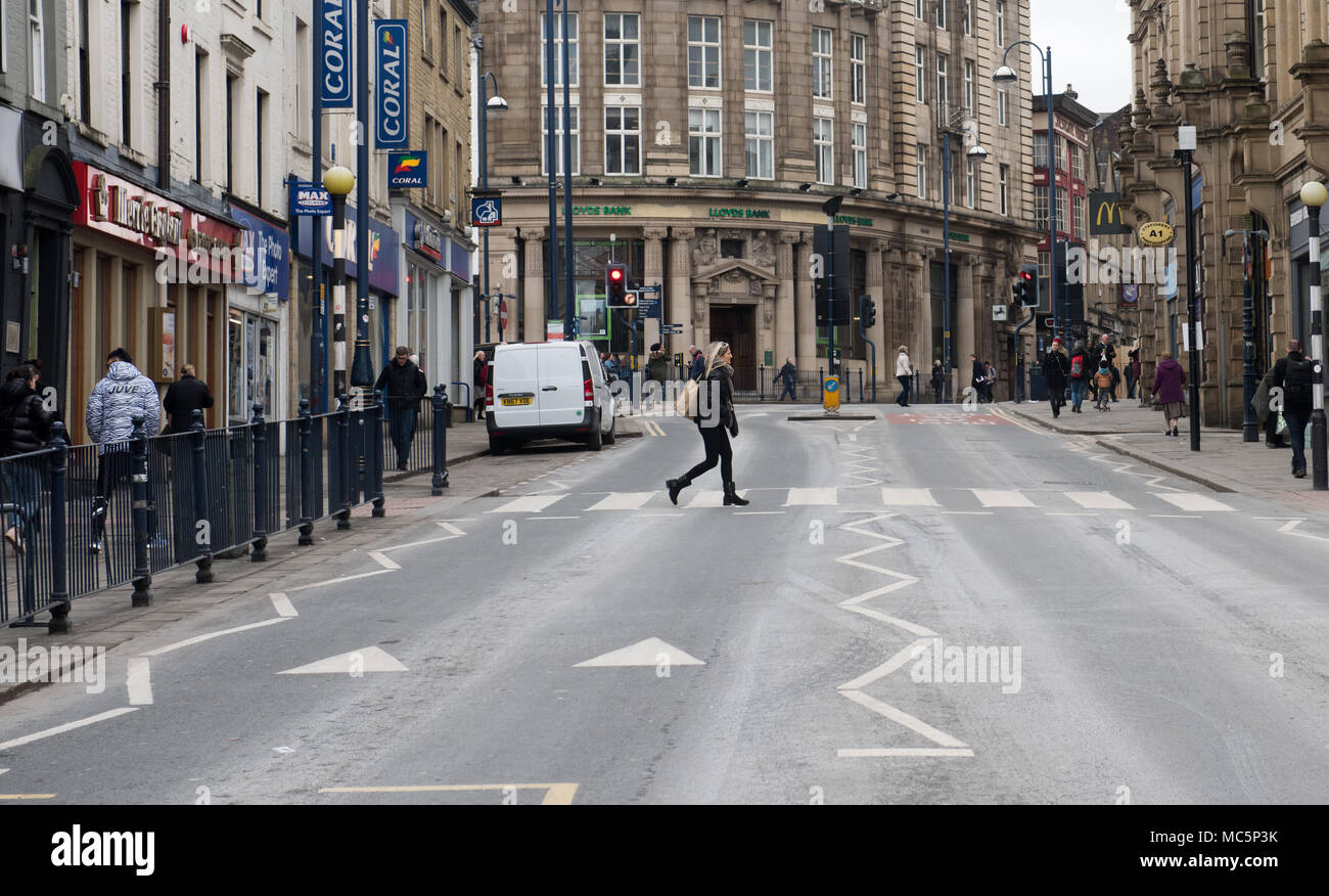 Eine belebte Straßenszene in einem britischen Stadtzentrum mit Fußgängern, die auf Wegen fahren, umgeben von historischer Architektur und Geschäften Stockfoto