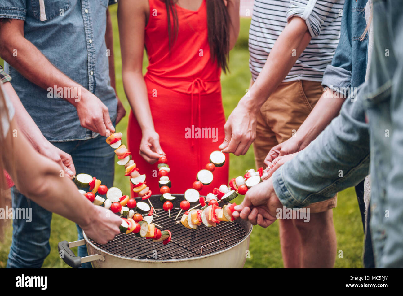 Gruppe von Freunden grillen shashliks während einer Grillparty, stehen in einem Kreis Stockfoto