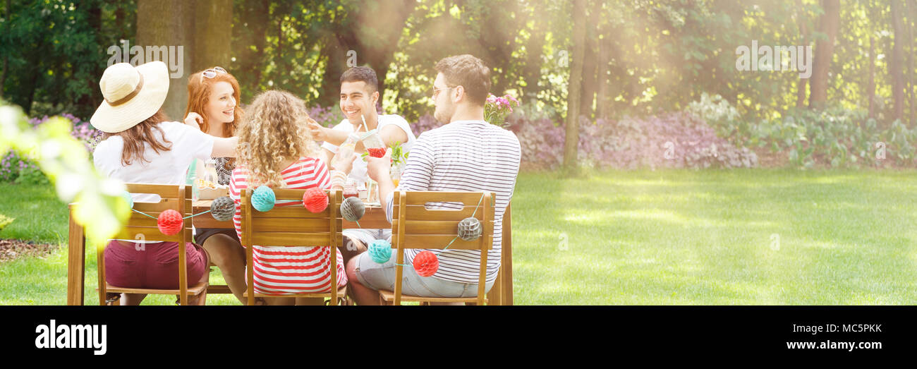 Panorama der glückliche Freunde beim Mittagessen im Garten während