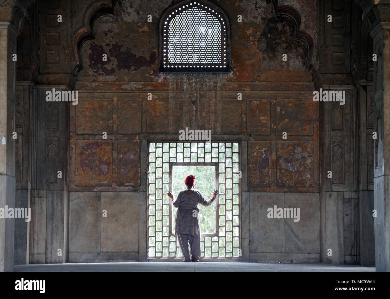 Indische Frau, die durch ein Fenster auf das Red Fort, Delhi, Indien Stockfoto