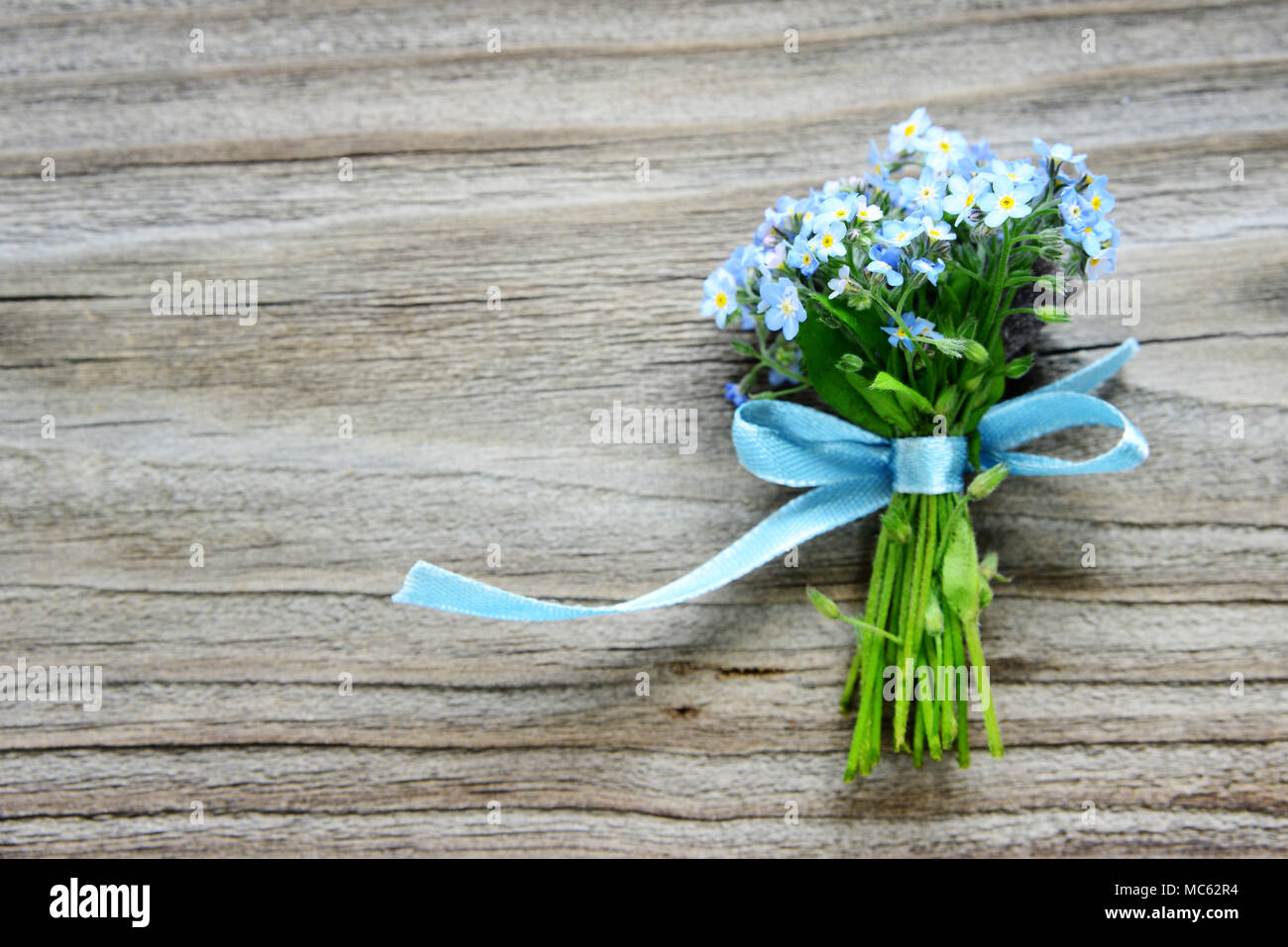 Kleinen Blumenstrauß aus blauen Vergißmeinnicht Blumen, mit einem blauen Band gebunden, auf dem Hintergrund der alten Holzbrett, mit copy-Raum Stockfoto