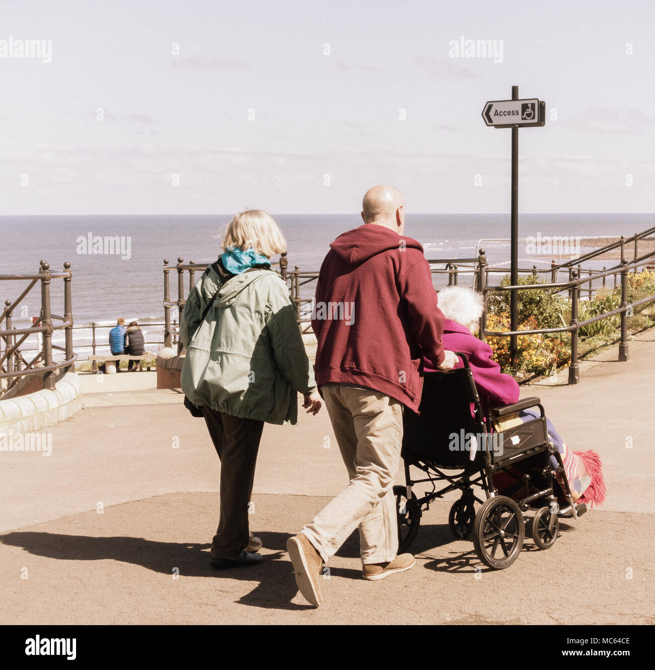 Paare und ältere Frau im Rollstuhl in der Nähe von Strand. Pflege älterer Eltern/Person... Stockfoto
