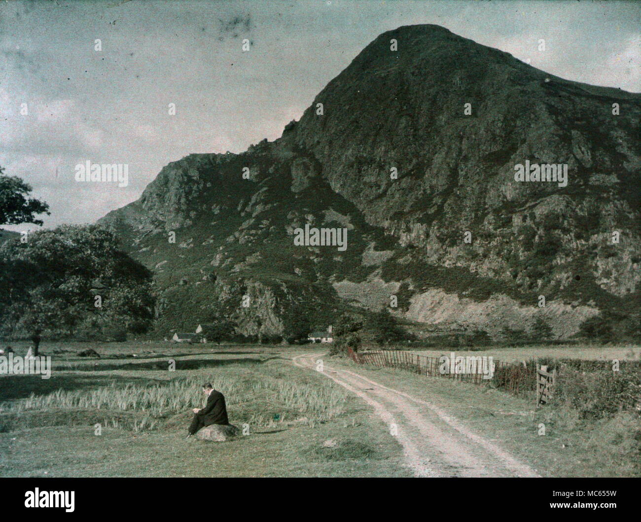 AJAXNETPHOTO. 1920 s (CA.). MERIONETHSHIRE, WALES, VEREINIGTES KÖNIGREICH. EIN MANN, DER EIN BUCH VOR EINEM BERG LIEST, EIN BLICK MIT EINEM FRÜHEN AUTOKROME-FARBFILM. FOTOGRAF:UNBEKANNT © DIGITAL IMAGE COPYRIGHT AJAX VINTAGE PICTURE LIBRARY QUELLE: AJAX VINTAGE PICTURE LIBRARY COLLECTION REF:(C)AVL ACHM 1911 55 Stockfoto