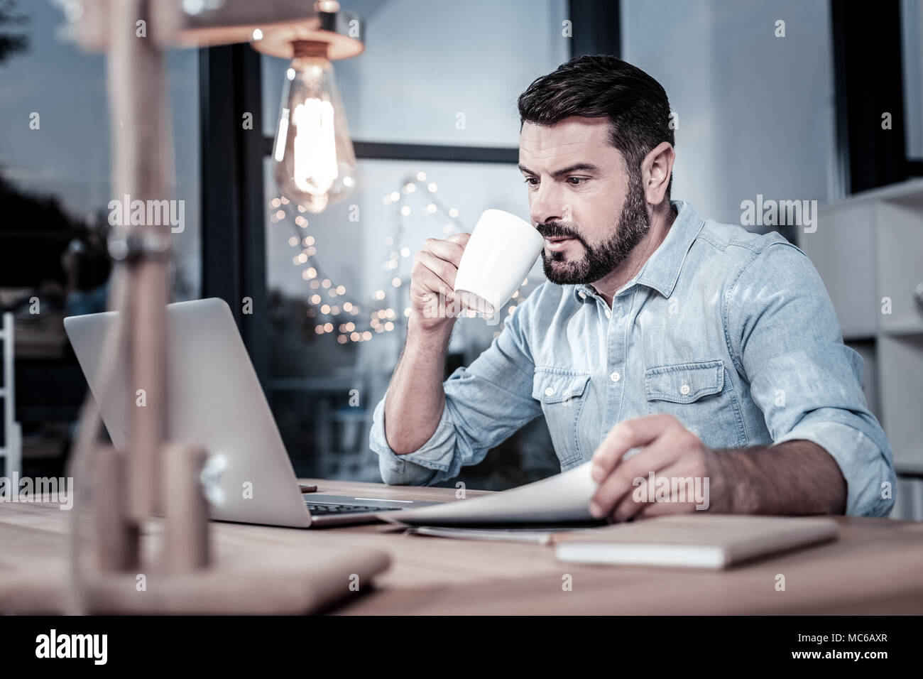 Konzentriert verantwortlichen Mann Tee trinken und auf Laptops. Stockfoto