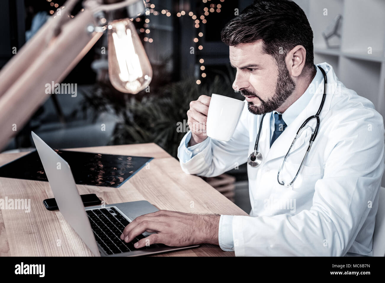 Unerschüttert besetzten Arzt mit Laptop halten einer Tasse Tee. Stockfoto