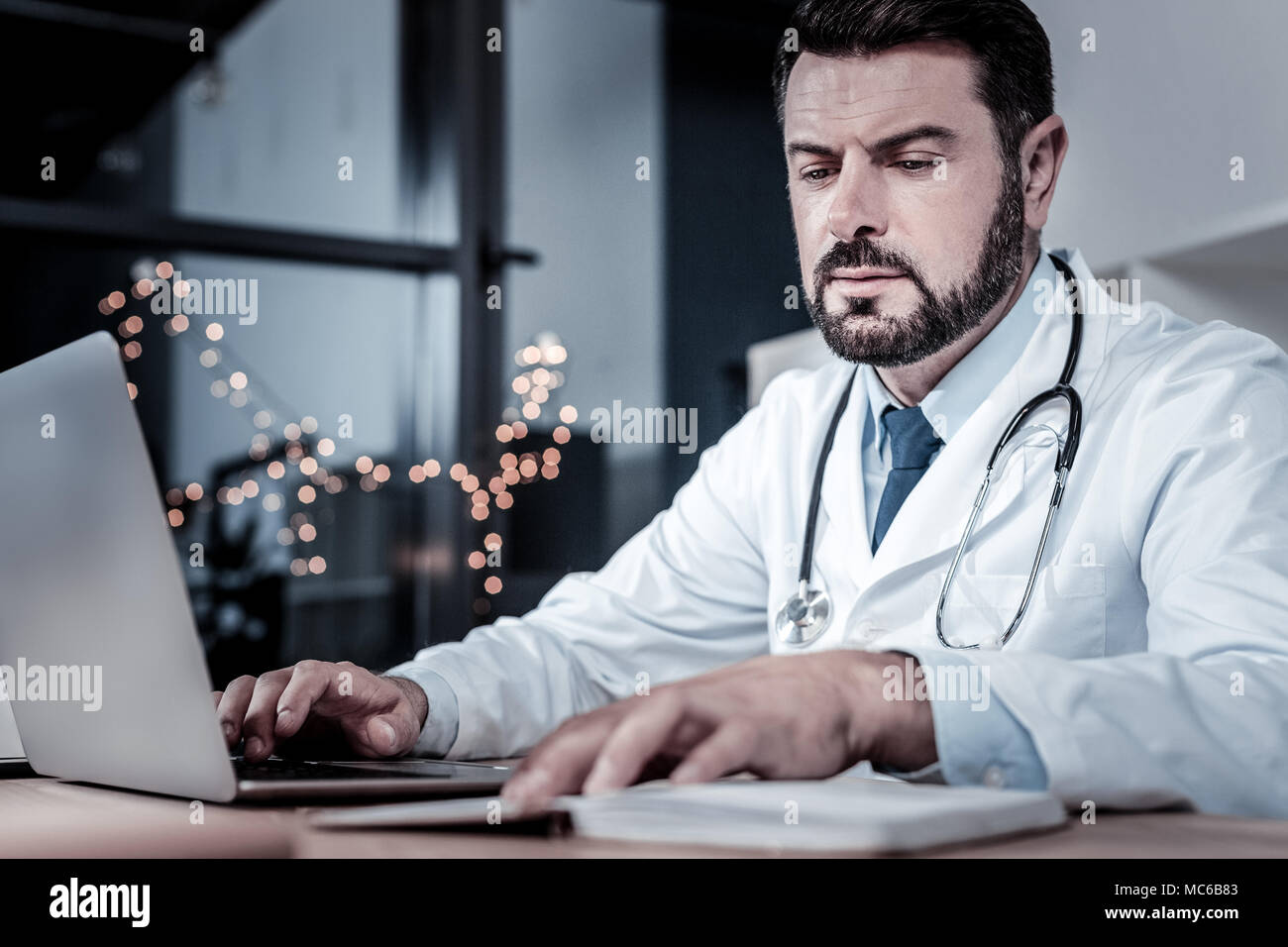 Unerschüttert Arzt sitzen und lesen seine Notizen belegt. Stockfoto