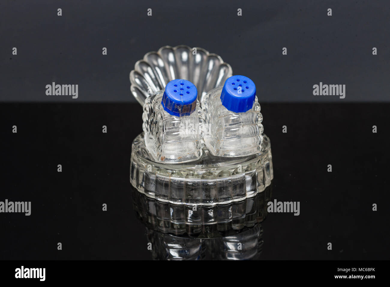 Ein Glas Salz- und Pfefferstreuer sitzen auf ein klares Glas Plattform Stockfoto
