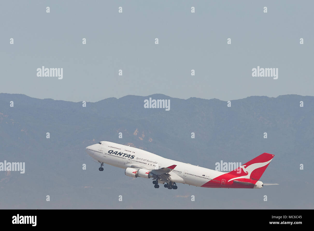 Qantas Airways Boeing 747-400 Jet Klettern entfernt vom internationalen Flughafen von Los Angeles, LAX. Der Santa Monica Mountains im Hintergrund. Stockfoto