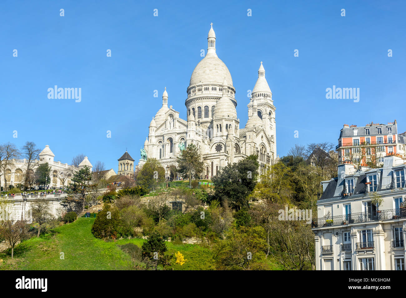 Die Basilika des Heiligen Herzen von Paris auf dem Montmartre mit der Louise Michel Park unterhalb und Apartment Gebäuden im Vordergrund. Stockfoto Die Basilika des Heiligen Herzen von Paris auf dem Montmartre mit der Louise Michel Park unterhalb und Apartment Gebäuden im Vordergrund. Stockfoto