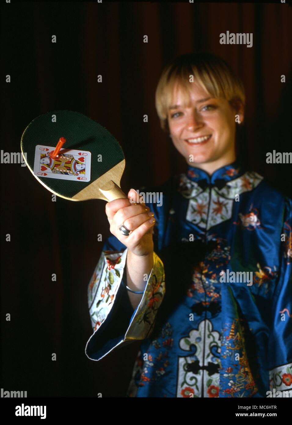 Stufe Magic-Shooting eine Karte. Der Magier hat ein Zuschauer eine Karte aus. Er legt die Karte wieder zurück in die Packung und stellt sie auf den Tisch. Er schießt auf der Assistant bat und die gewählte Karte wird es gepinnt. String wird hier verwendet, um zu zeigen, wie der Trick getan ist. Stockfoto