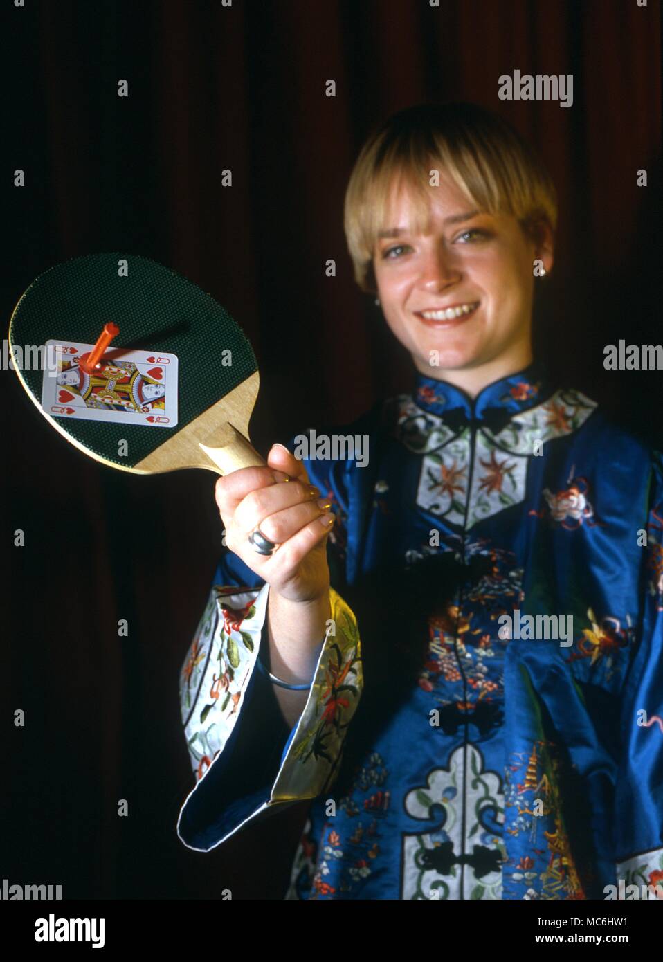 Stufe Magic-Shooting eine Karte. Der Magier hat ein Zuschauer eine Karte aus. Er legt die Karte wieder zurück in die Packung und stellt sie auf den Tisch. Er schießt auf der Assistant bat und die gewählte Karte wird es gepinnt. String wird hier verwendet, um zu zeigen, wie der Trick getan ist. Stockfoto