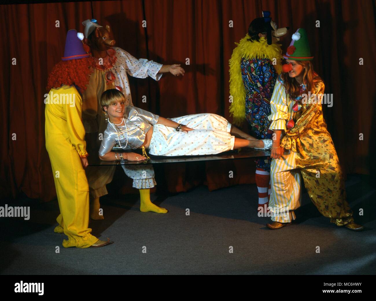 Stufe Magic-verschwinden Mädchen. Ein Mädchen ist auf einer Glasplatte, die von einer Gruppe von Clowns durchgeführt. Stockfoto