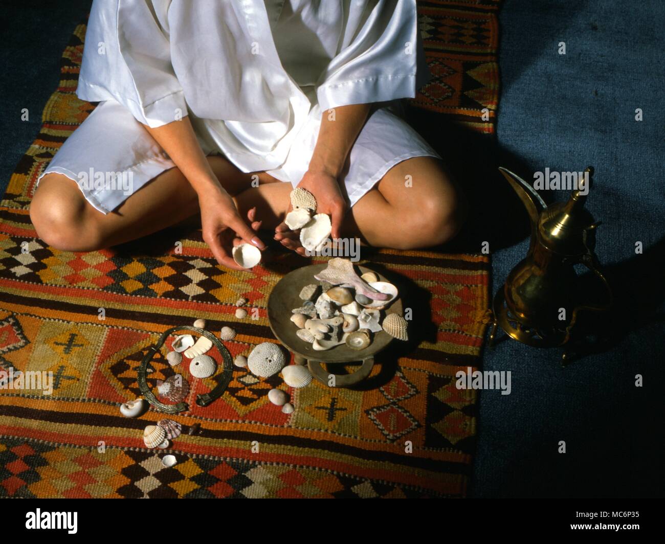 Geomantie sitzende Mädchen werfen Steine und Muscheln in einen Teppich Muster, als Auftakt für die Gründung der geomantischen Zahlen in der Antwort auf eine Frage. 2004 Charles Walker/ Stockfoto