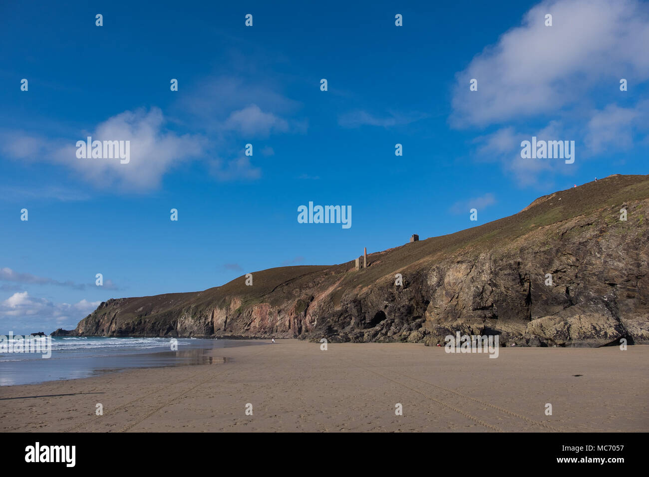 Cornish Zinnmine oberhalb der Klippen auf einem hellen, sonnigen Tag der weißen Wolken und vivd blauer Himmel mit Blick auf den Strand und das Meer. Stockfoto