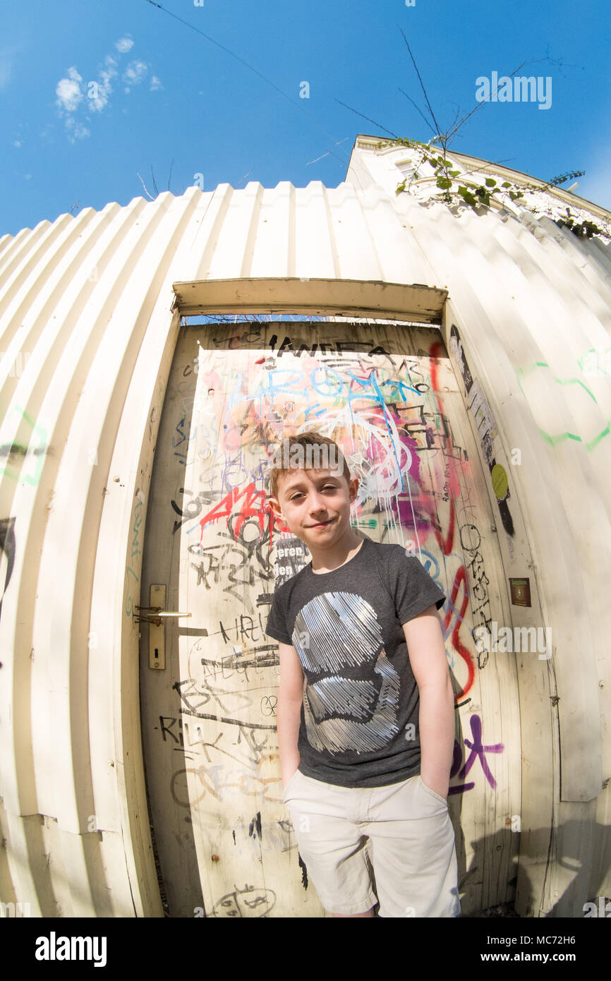 Acht Jahre alter Junge stand vor der Tür ein Graffiti bedeckt, Wien, Österreich, Europa. Stockfoto