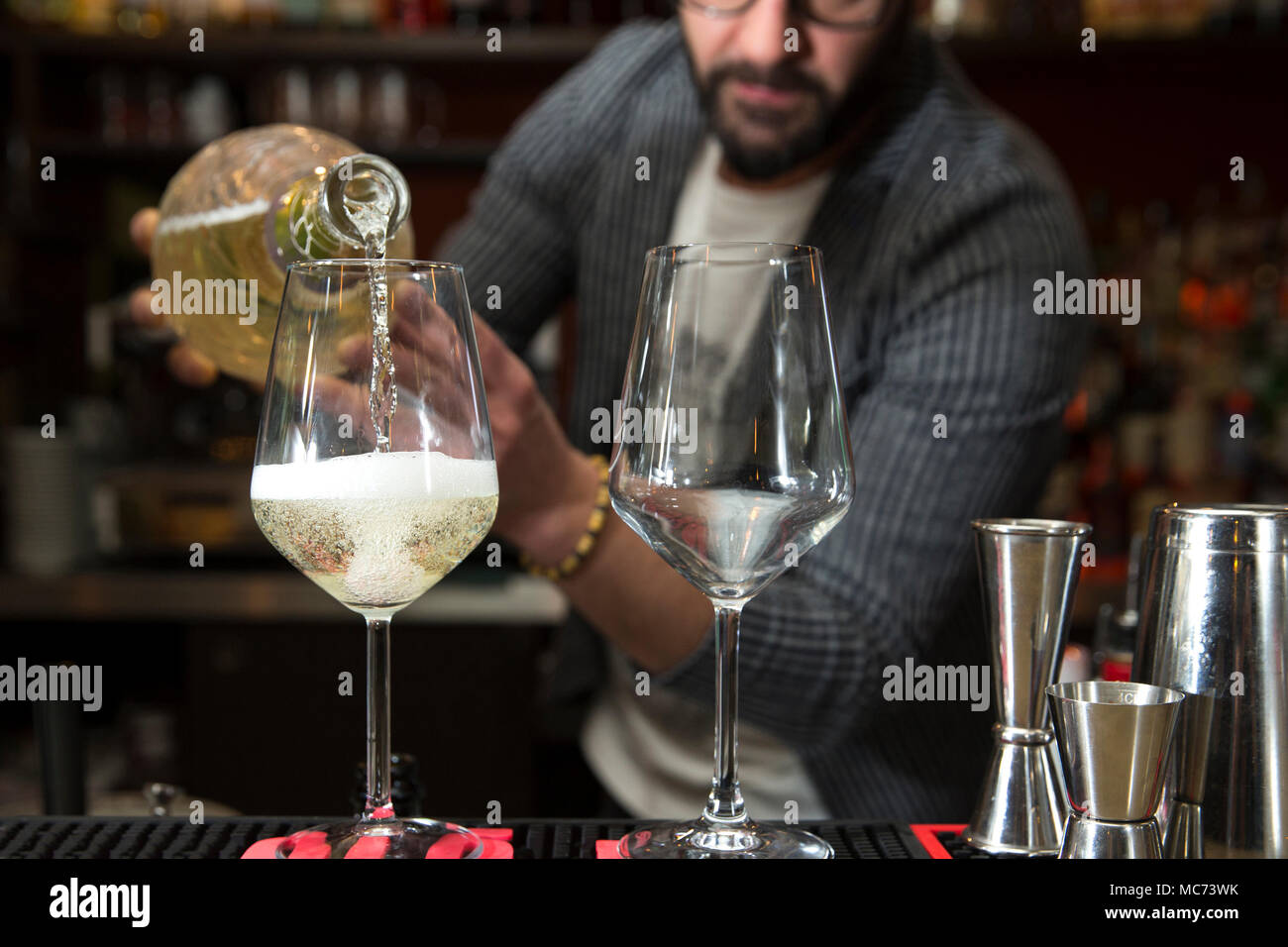 Nahaufnahme von einem Barkeeper arbeiten hinter einer Theke, Prosecco, Abfüllung in zwei Weingläser mit Fokus auf die Gläser Stockfoto