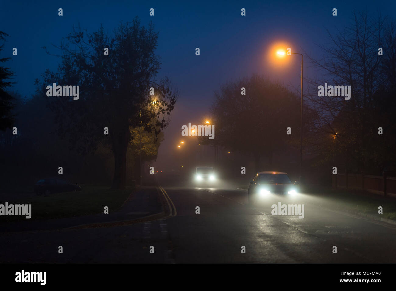 Fahrzeuge, die nachts auf einer Vorstadtstraße in England unterwegs sind. Stockfoto