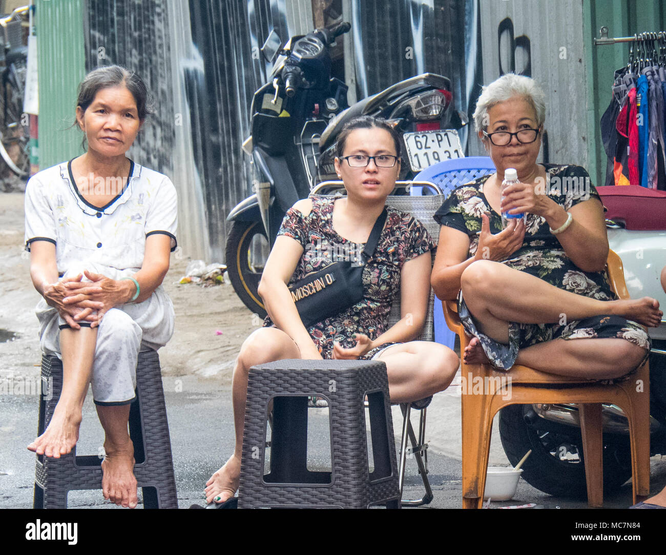 Drei vietnamesische Frauen sitzen auf Plastikstühlen auf dem Bürgersteig die Straße Tätigkeiten in Ho Chi Minh City, Vietnam. Stockfoto