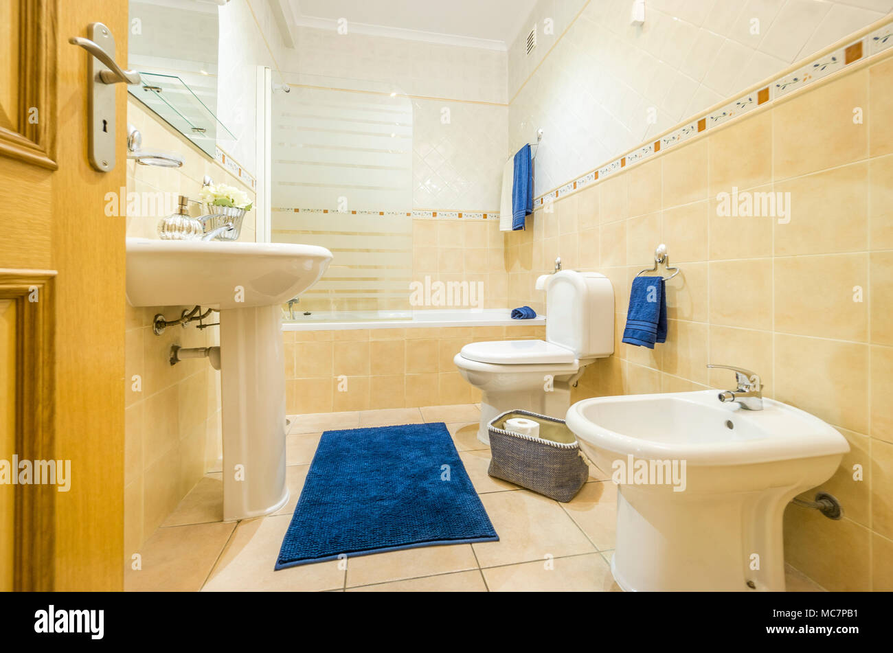 Klassik Bad in warmen Farben und mit blauer Bettwäsche und Decke Stockfoto