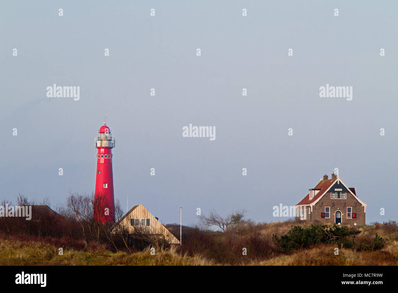 Rote Leuchtturm und drei Häuser in den Dünen der holländischen Insel Schiermonnikoog Stockfoto