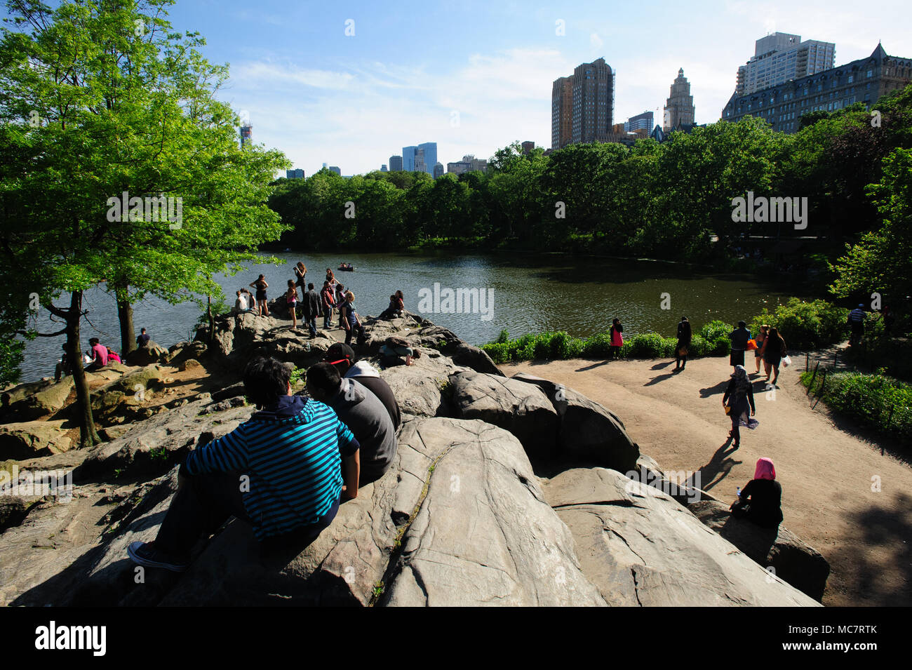 Die Leute sitzen auf den Felsen mit Blick auf die Skyline der Stadt im Central Park, Manhattan, New York City, im Mai 2013. Stockfoto