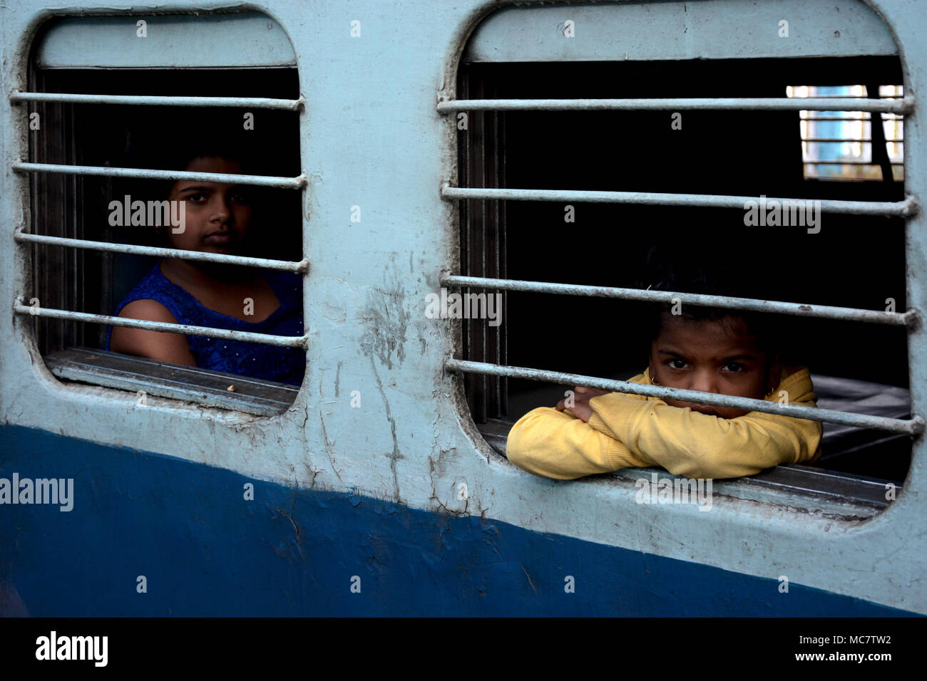 Mädchen und Jungen von den vergitterten Fenster eines indischen Zug, Mumbai gebunden Stockfoto