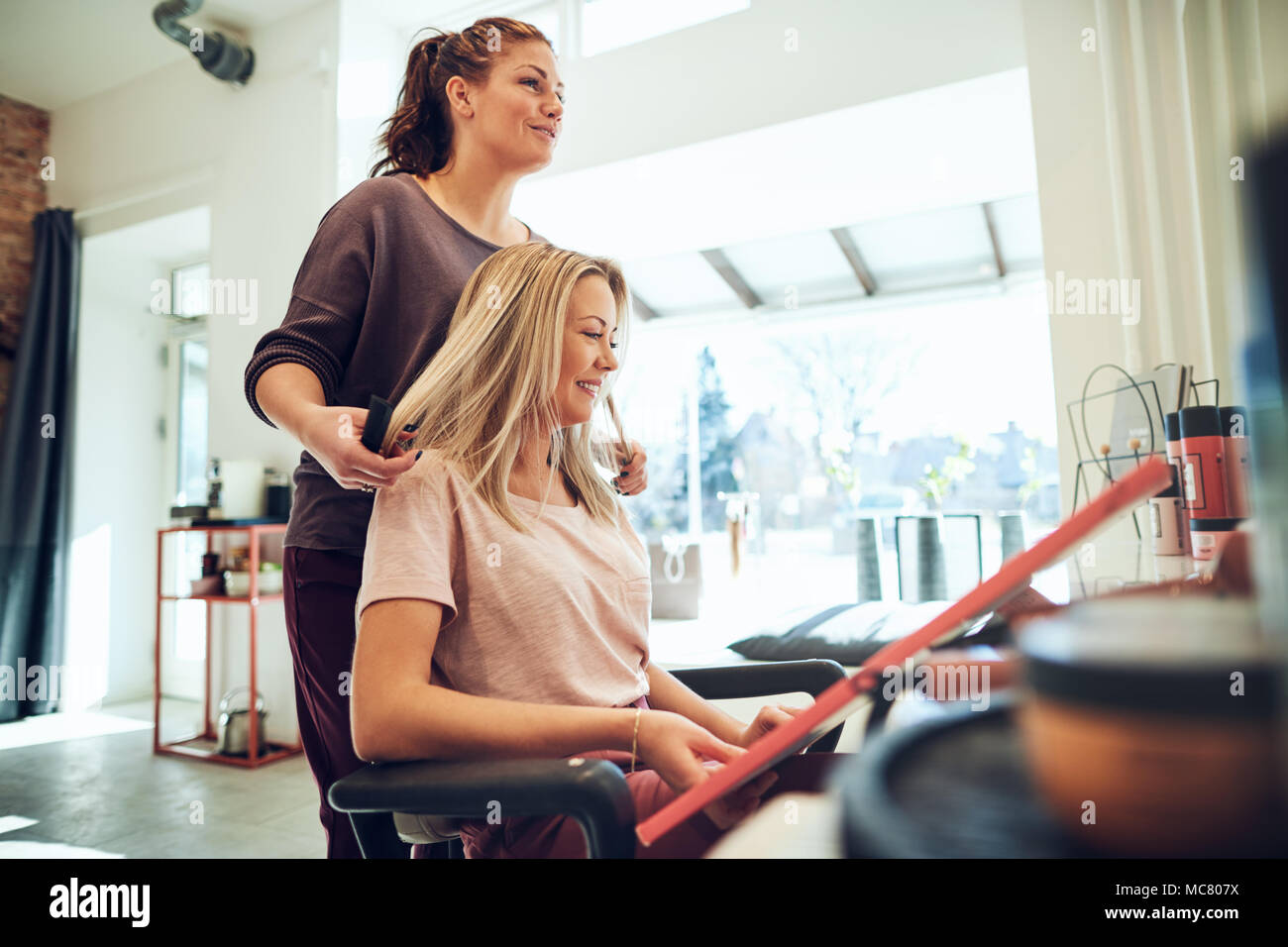 Junge Blonde Frau Die Wahl Eines Neuen Haarfarbe Von Proben In Einem Buch Mit Ihrem Friseur Wahrend Im Salon Stuhl Stockfotografie Alamy