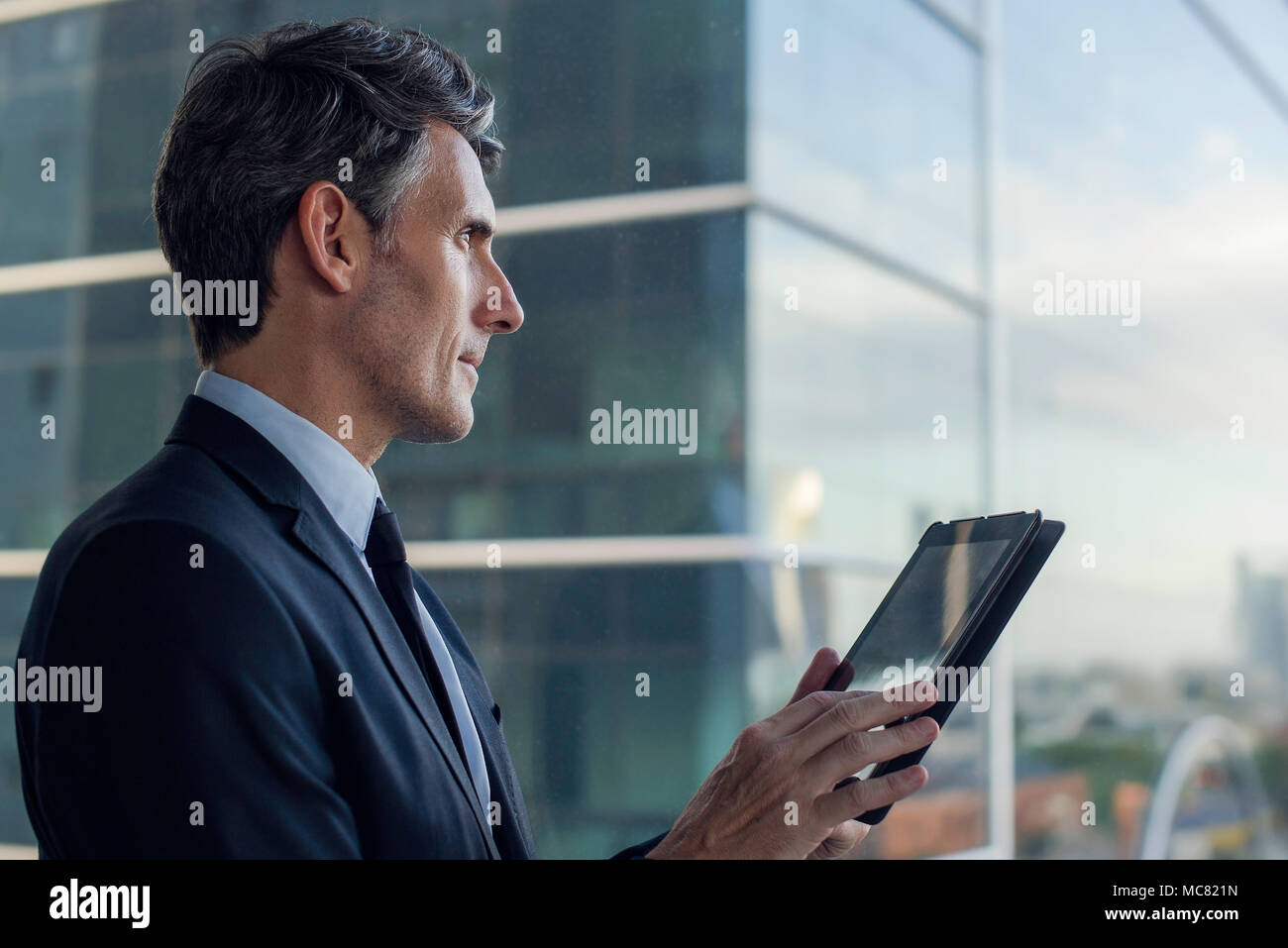 Mann mit digitalen Tablet von Fenster in Hochhaus Stockfoto