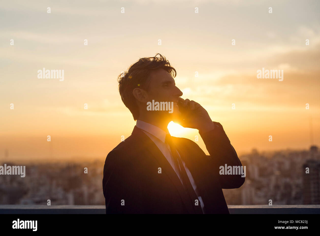 Mann mit Handy zurück, die von der untergehenden Sonne leuchtet Stockfoto