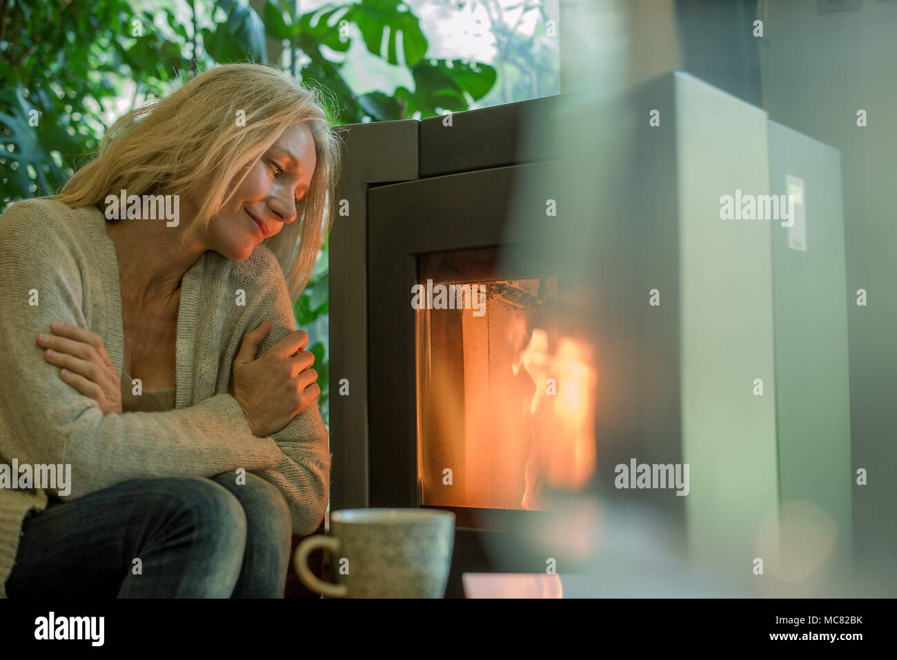 Reife Frau Entspannen am Kamin Stockfoto