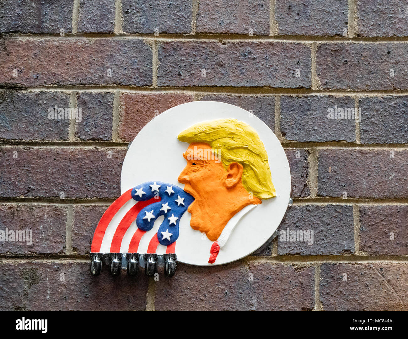 Wall Plaque in Bristol UK Stadtzentrum Gasse mit Donald Trump Amerika setzen erste Herauszuspritzen ein Sternenbanner Flagge mit Bomben auf jedem Stripe Stockfoto