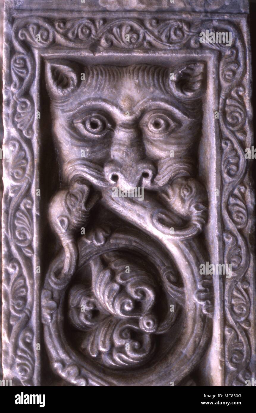 Dämonischen Kopf schlucken Reben ranken, oder Laub von inerlace, auf der Tierkreiszeichen Bogen von Sagrada di San Michele, in der Val di Susa [Italien]. Diese Skulptur ist Teil der Tierkreiszeichen Satellitenbilder auf der Treppe der Toten in diesem alten Kloster. Stockfoto