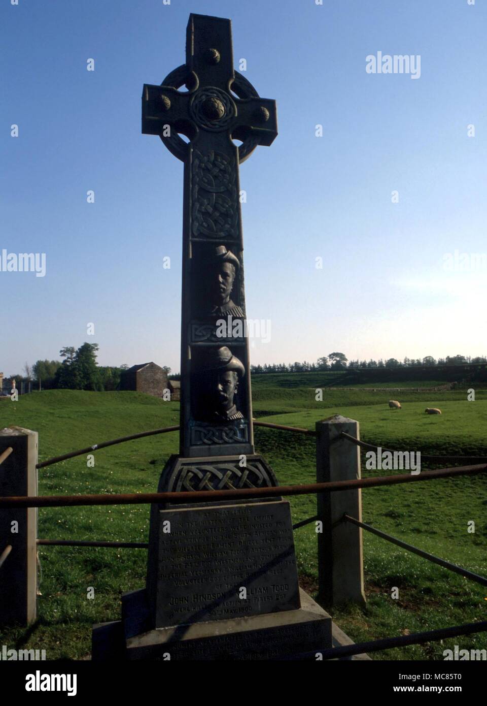 Christlichen Mythos - Eamont Bridge (Denkmal) Kreuz Denkmal für die lokale Männer im Burenkrieg getötet, mit erhöhten Gesichtsbehandlung Bildnisse. Nördlich der prähistorischen graben System als 'Arthur's Round Table" Stockfoto