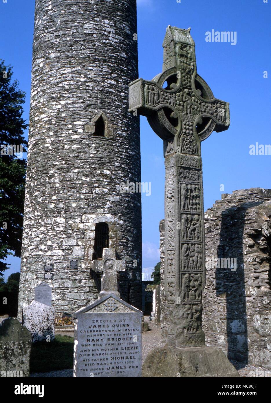 CELTIC im 10. Jahrhundert der 'Westen' von Monasterboice, mit dem runden Turm im Hintergrund. Das Kreuz ist 7 Meter hoch. Das Thema des zentralen Chef ist Christus als Symbol der Kirche militanten Stockfoto