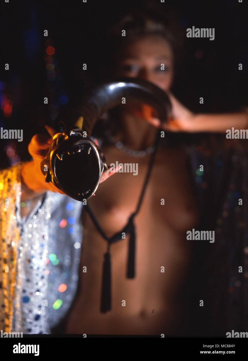 Frau weht ein schamane Horn Trompete mit dämonischen Kopf. Stockfoto