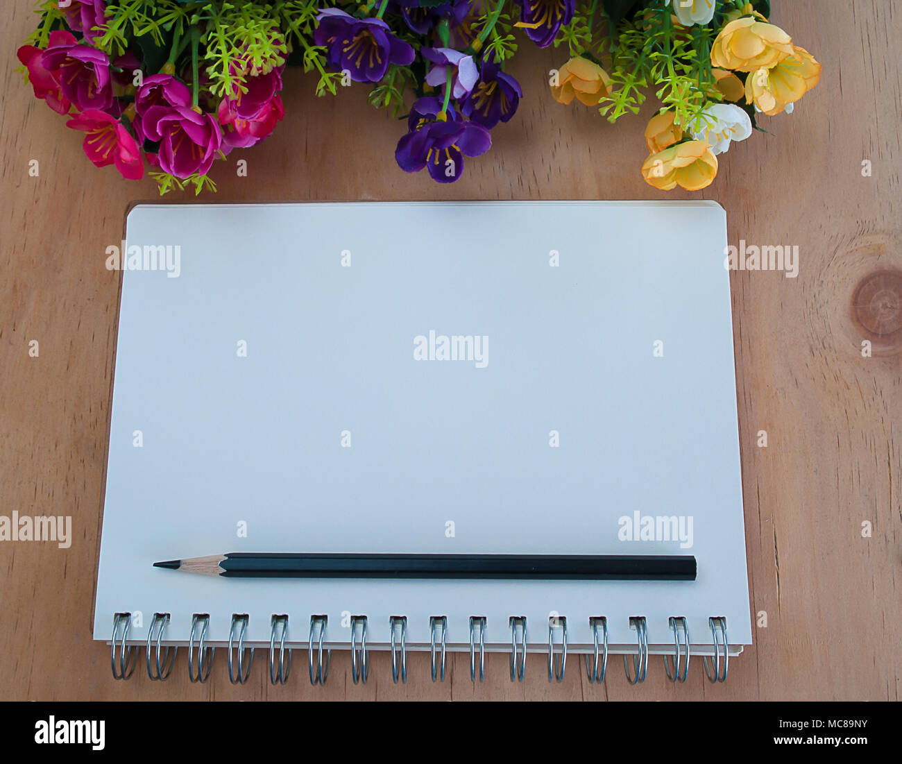 Tagebuch und Bleistift auf den Tisch legen und mit schönen Blumen. Stockfoto