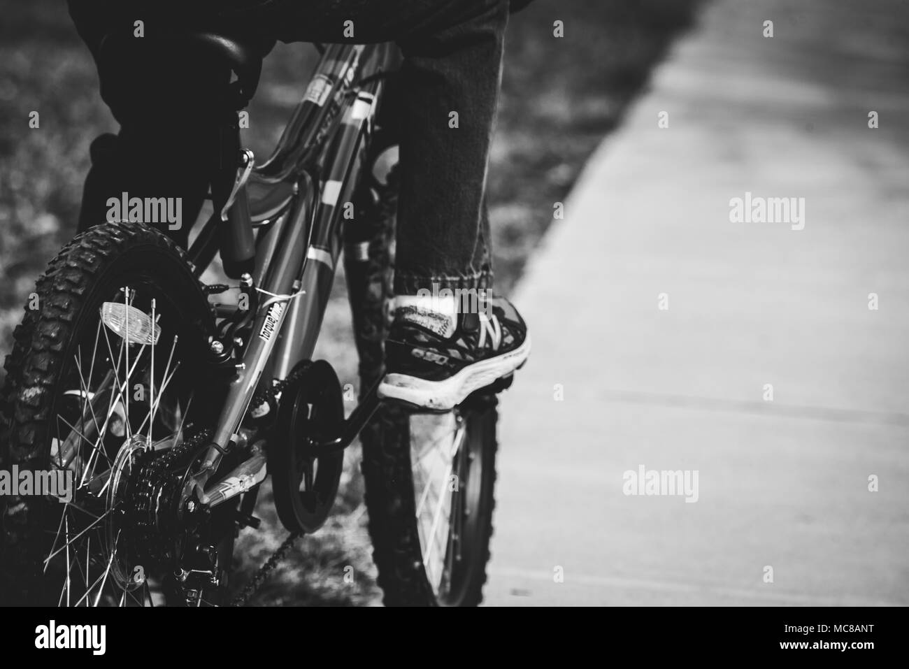 Ein Junge fährt mit dem Fahrrad auf einem Parkplatz im Frühjahr. Stockfoto