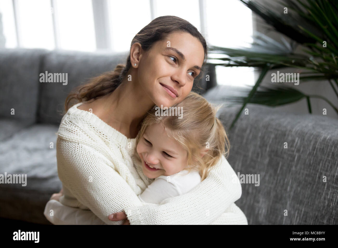 Liebevolle Mutter umarmt süsse kleine Tochter liebe Pflege unterstützen, glückliche Frau umarmt Vorschule Mädchen zu Hause, Mama und Kind herzlich warmen re Stockfoto