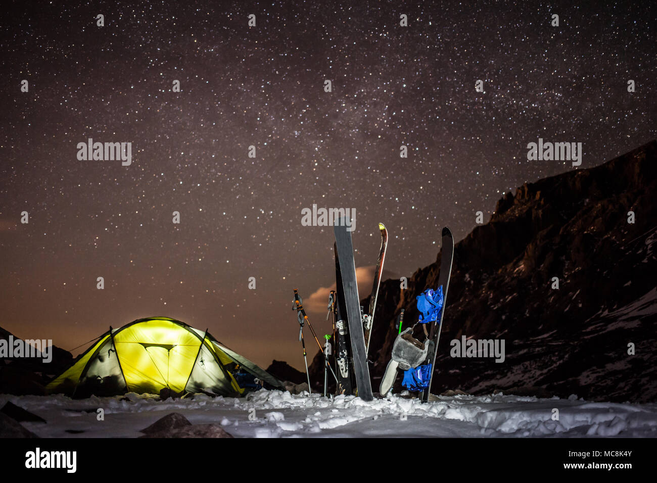 Backcountry camping mit Skiern und snowbords an Bogdanovich Gletscher in den Bergen in der Nähe von Almaty. Klare Himmel voller Sterne und leuchtende Zelt. Stockfoto