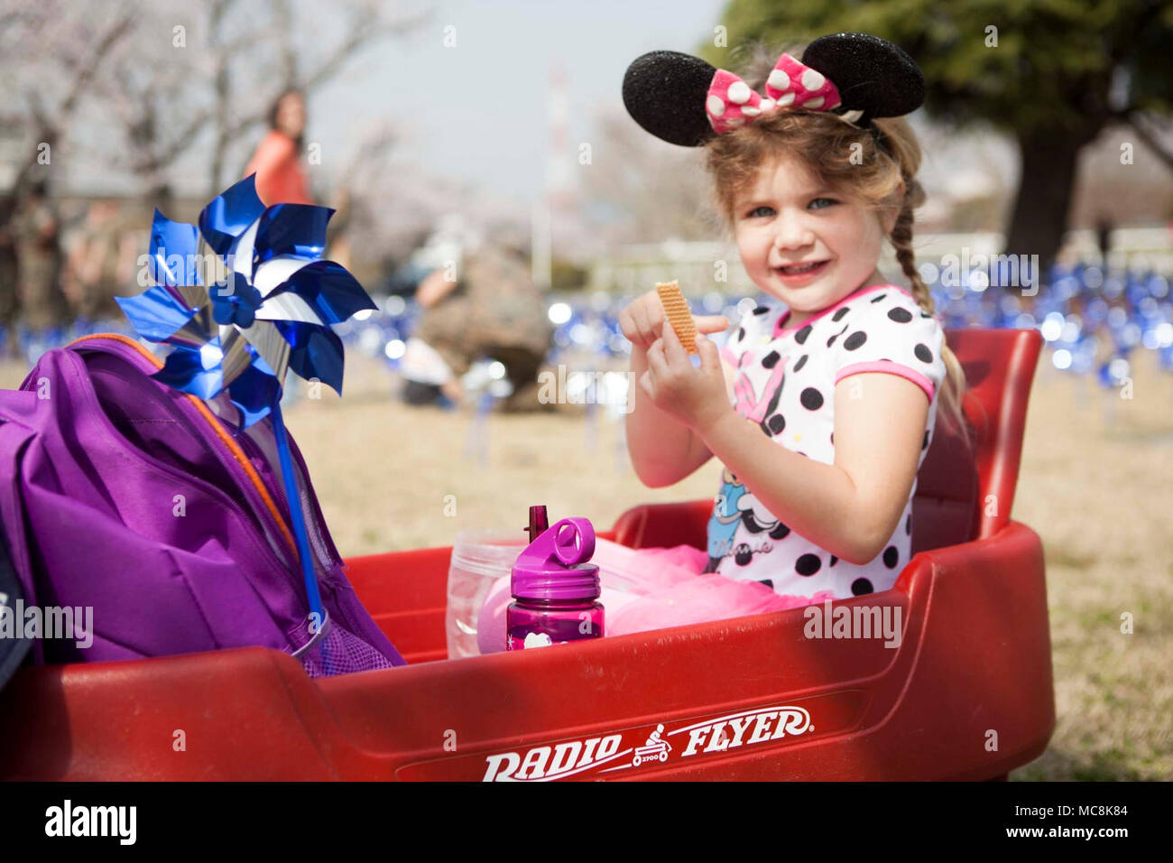 Ellie Katzenberger, Marine Corps Air Station Iwakuni (WAB) wohnen, isst Cracker während des 2018 National Child Abuse Prevention Pinwheel Pflanzen bei WAB Iwakuni, Japan, 29. März 2018. Die blauen Pinwheels wurden als Teil der nationalen Kindesmissbrauch Prävention Monat Aktivitäten gepflanzt und die Möglichkeit für Einzelpersonen und Organisationen, Maßnahmen zu ergreifen. Stockfoto