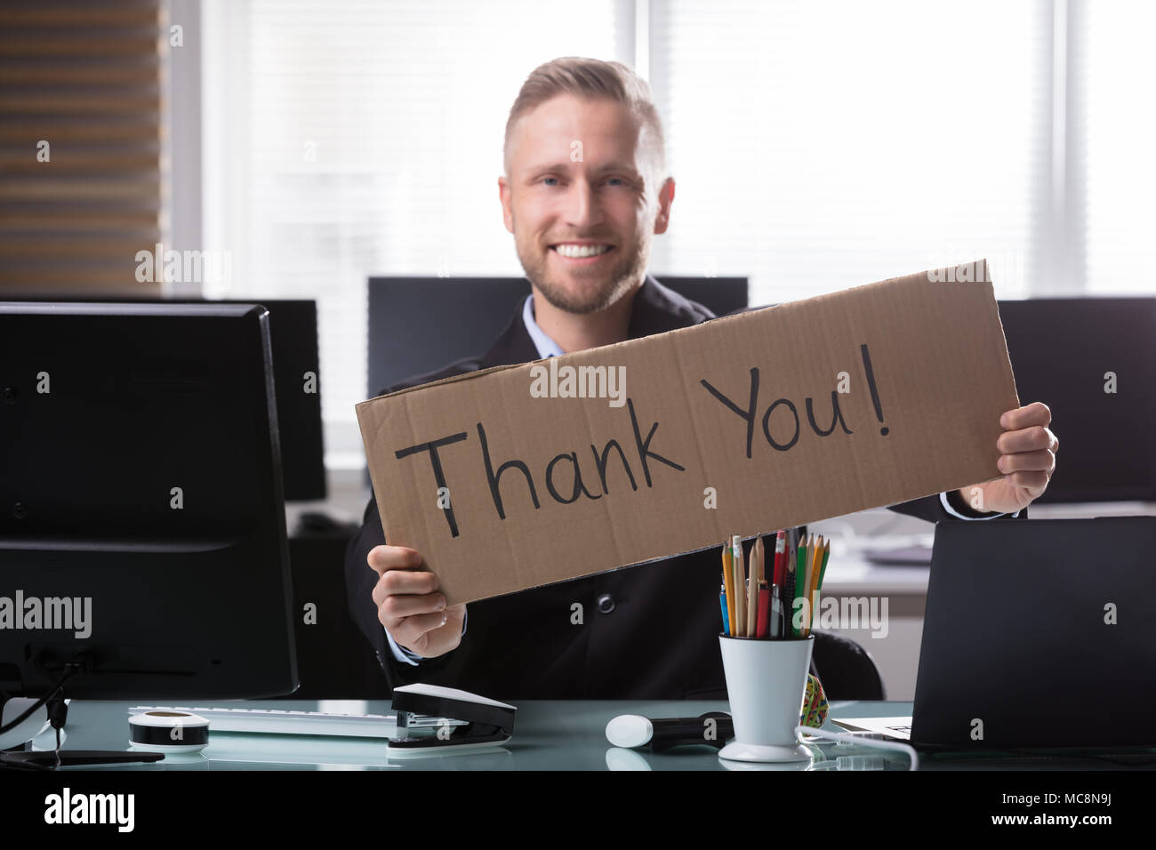 Porträt eines lächelnden Jungen Geschäftsmann Holding Pappe mit vielen Dank Text Stockfoto