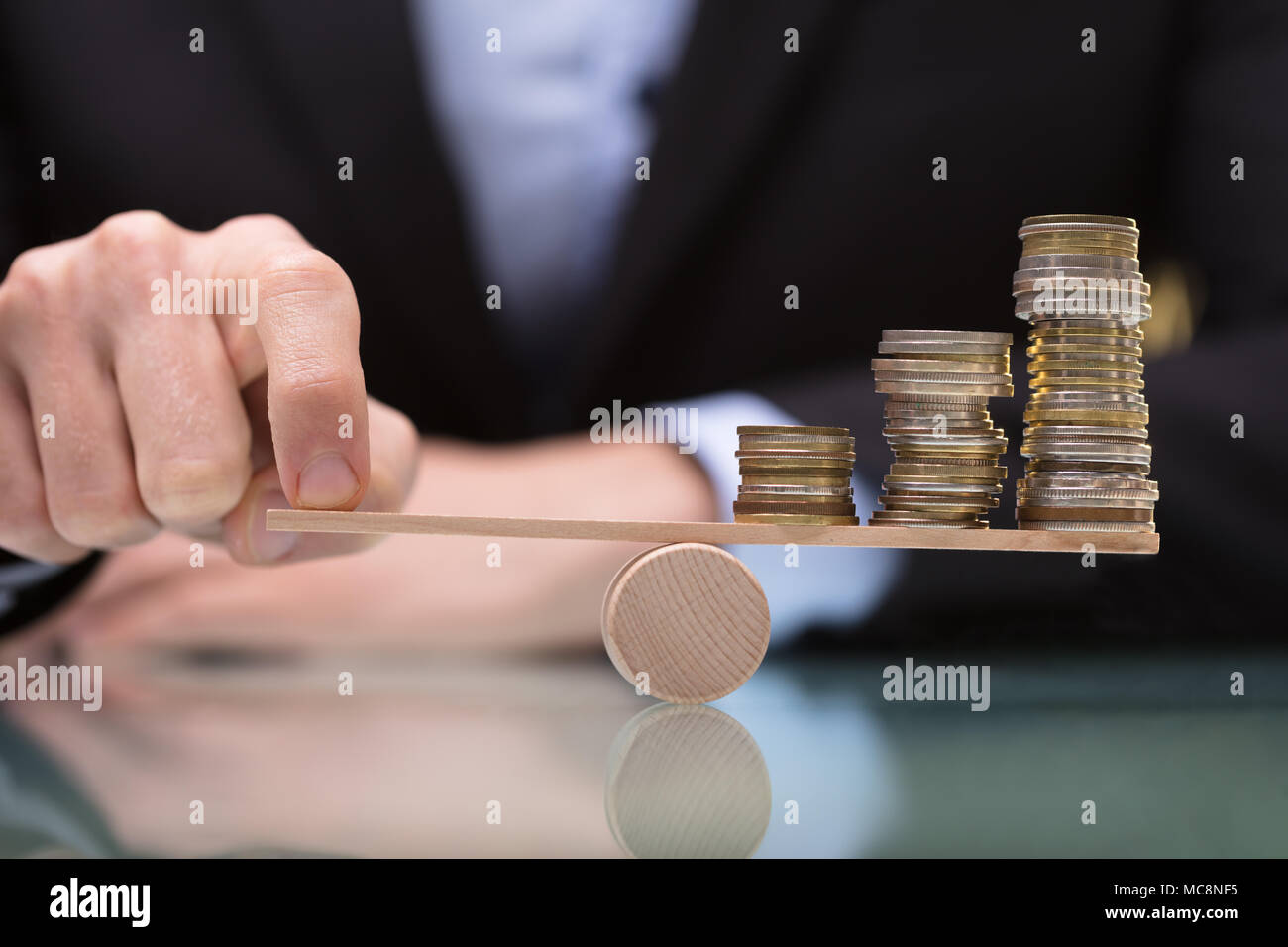 Nahaufnahme einer Businessperson Balancing gestapelte Münzen auf Wippe mit Finger Stockfoto