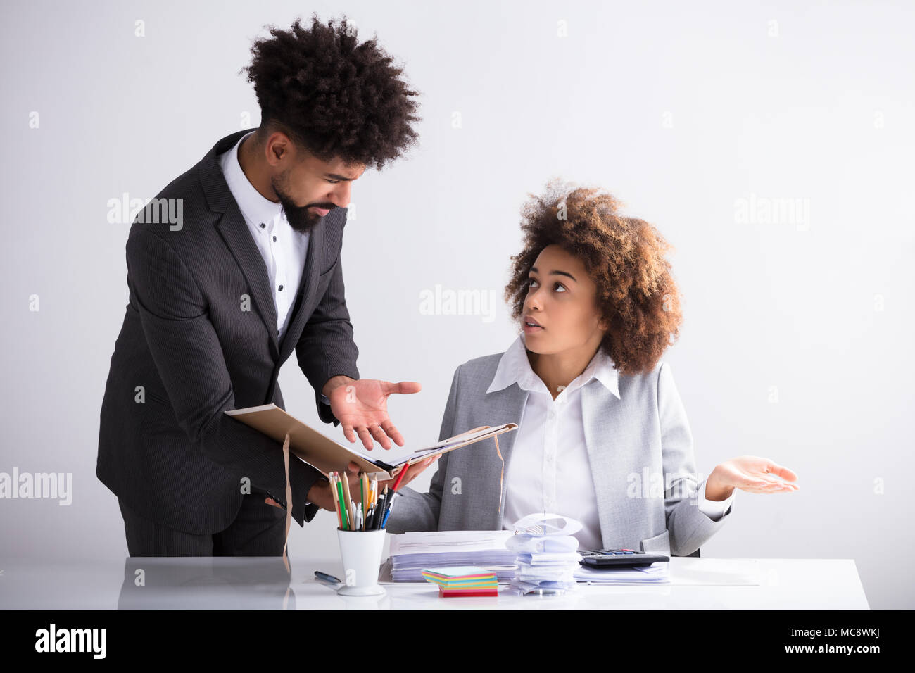Junge Unternehmer zeigt Fehler im Dokument zu seiner Kollegin am Arbeitsplatz Stockfoto